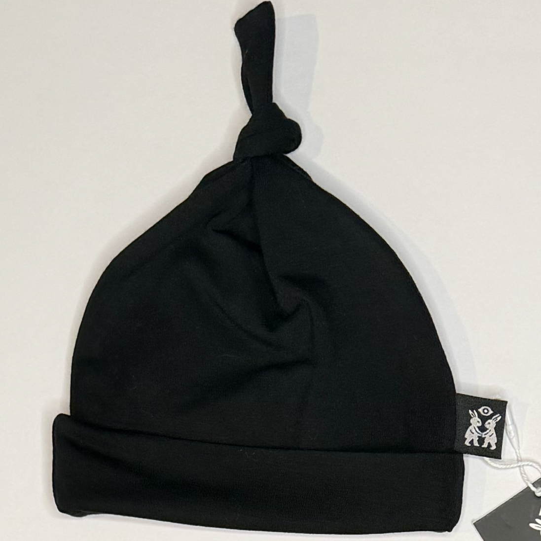Black baby hat with a tag on a light gray background