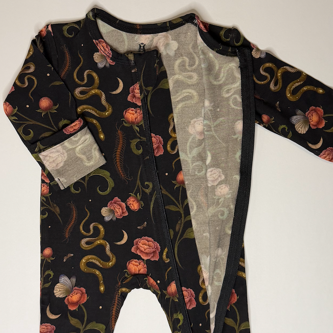 Baby onesie with snake and flower pattern on a white background