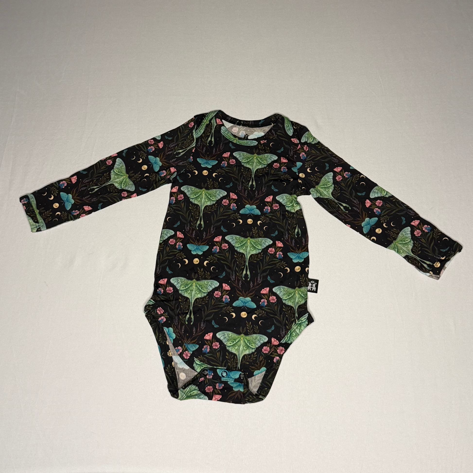 Black baby onesie with colorful moth pattern on a white background