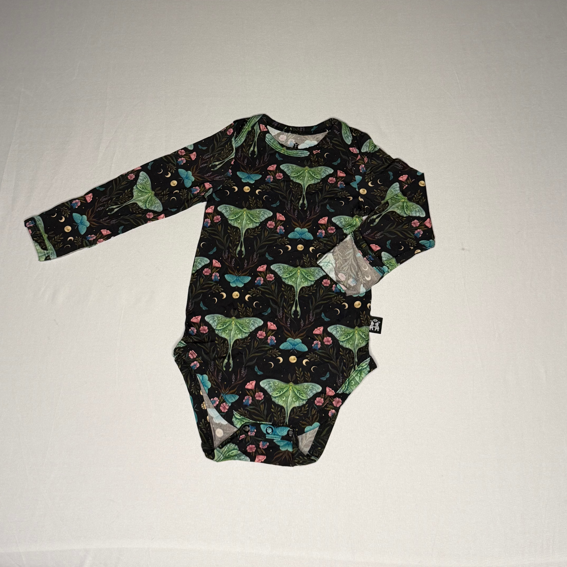 Black onesie with colorful moth or butterfly pattern on a white background