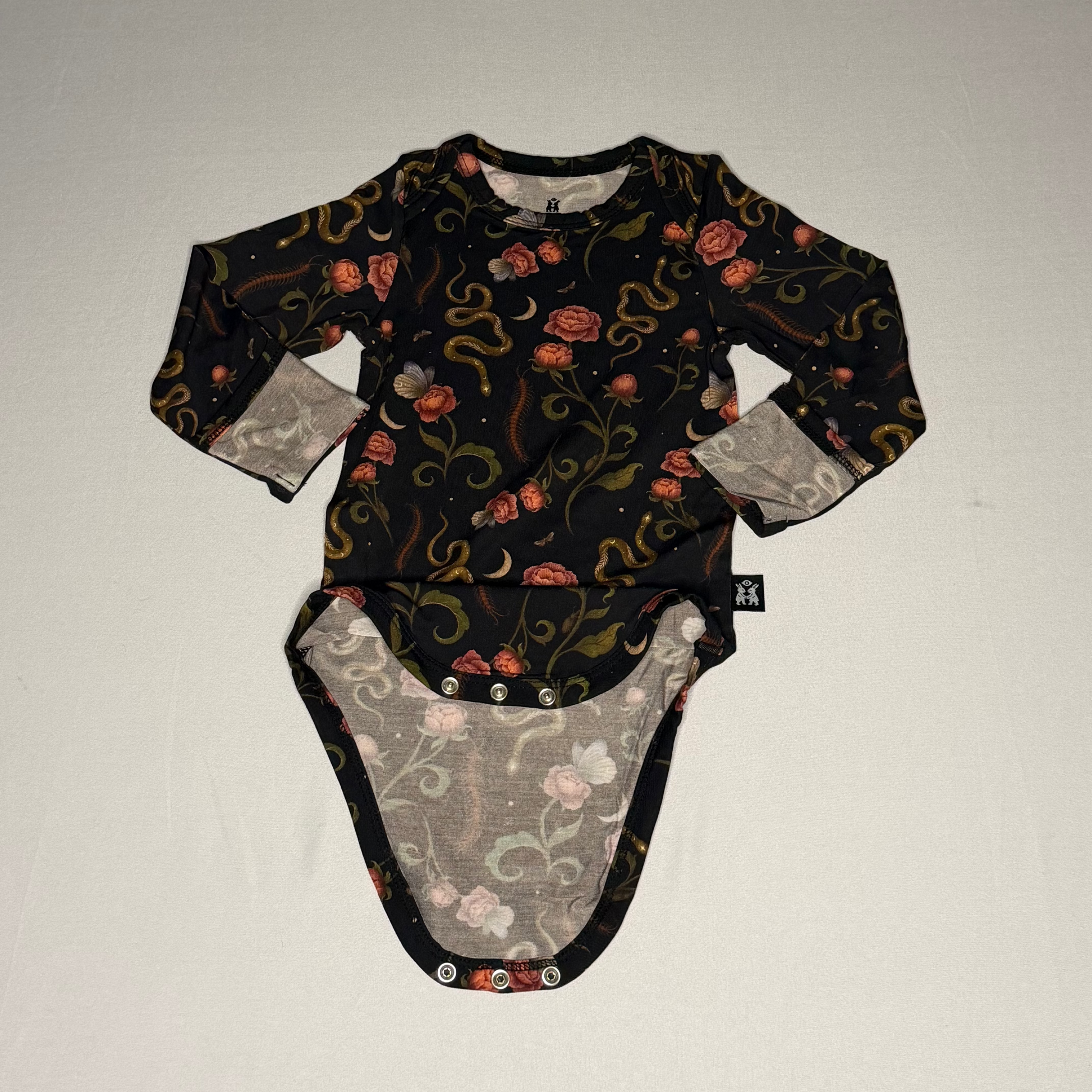 Baby onesie with floral and snake pattern on a plain background