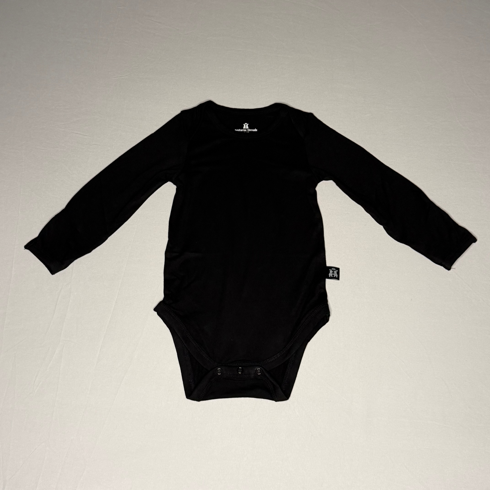 Black baby onesie on a light gray background