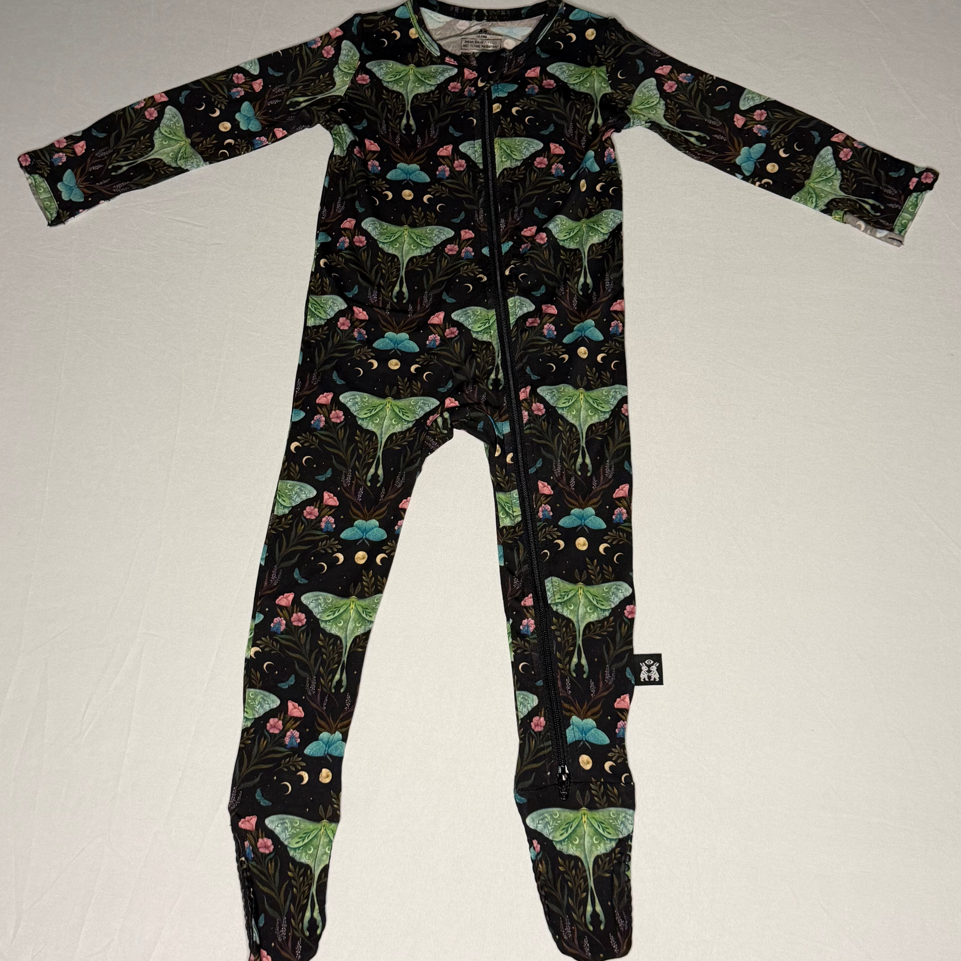 Children's onesie with green and black  moth pattern on a white background
