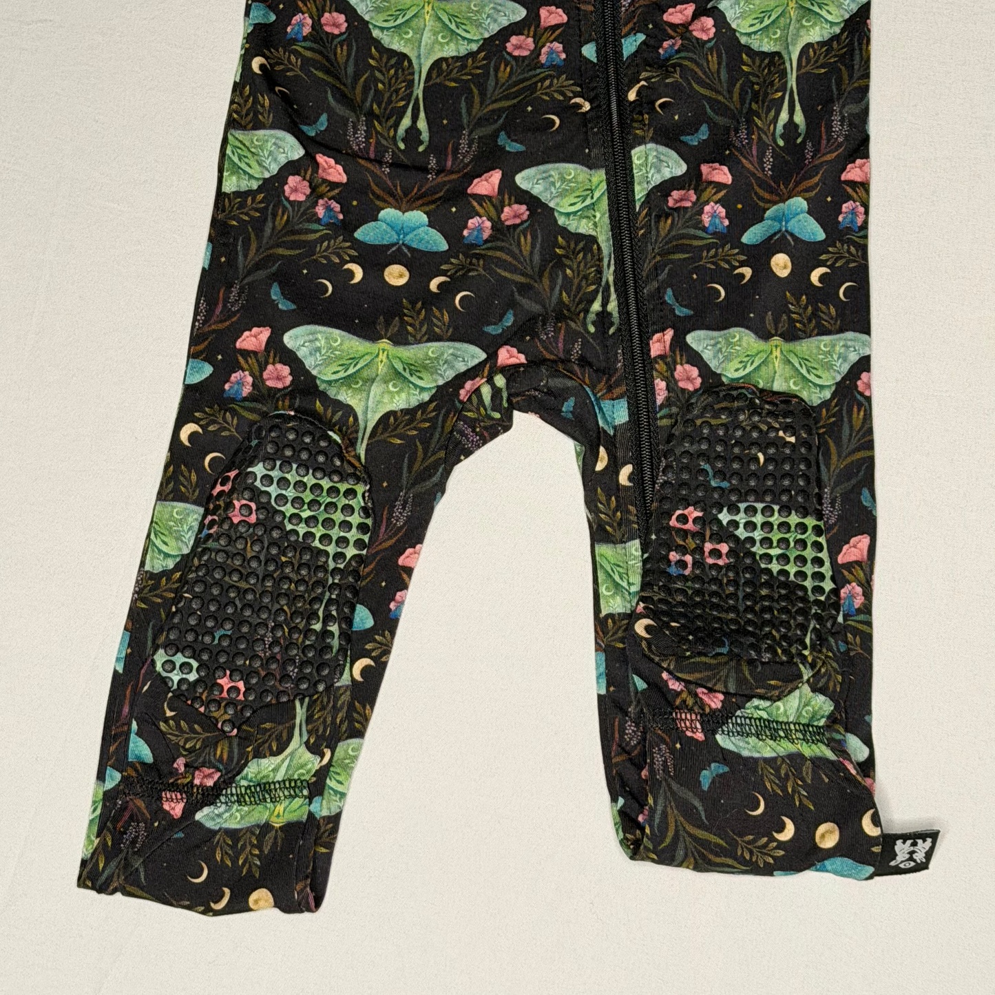 Children's footie with a colorful moth pattern on a white background