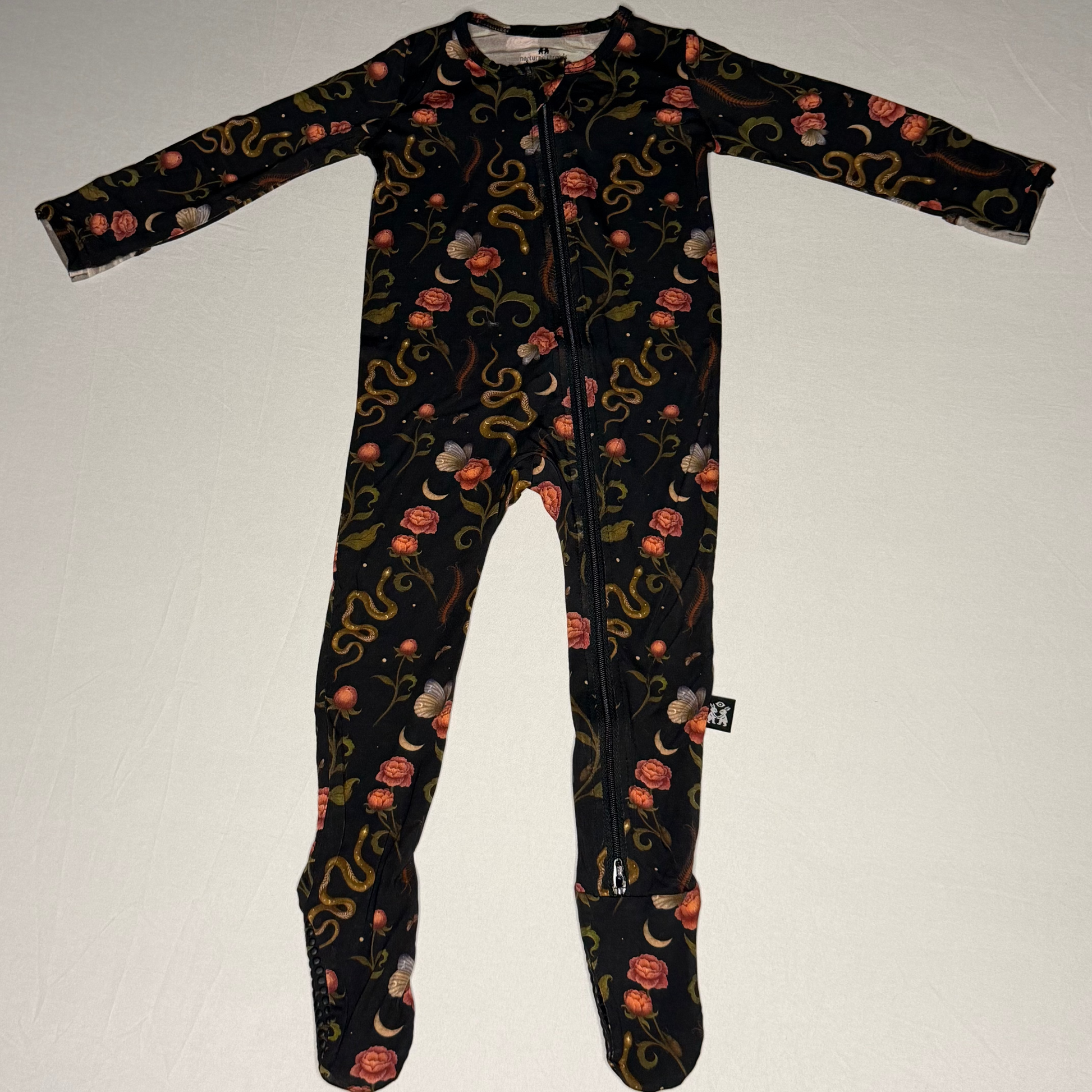 Black baby onesie with floral and snake pattern on a white background