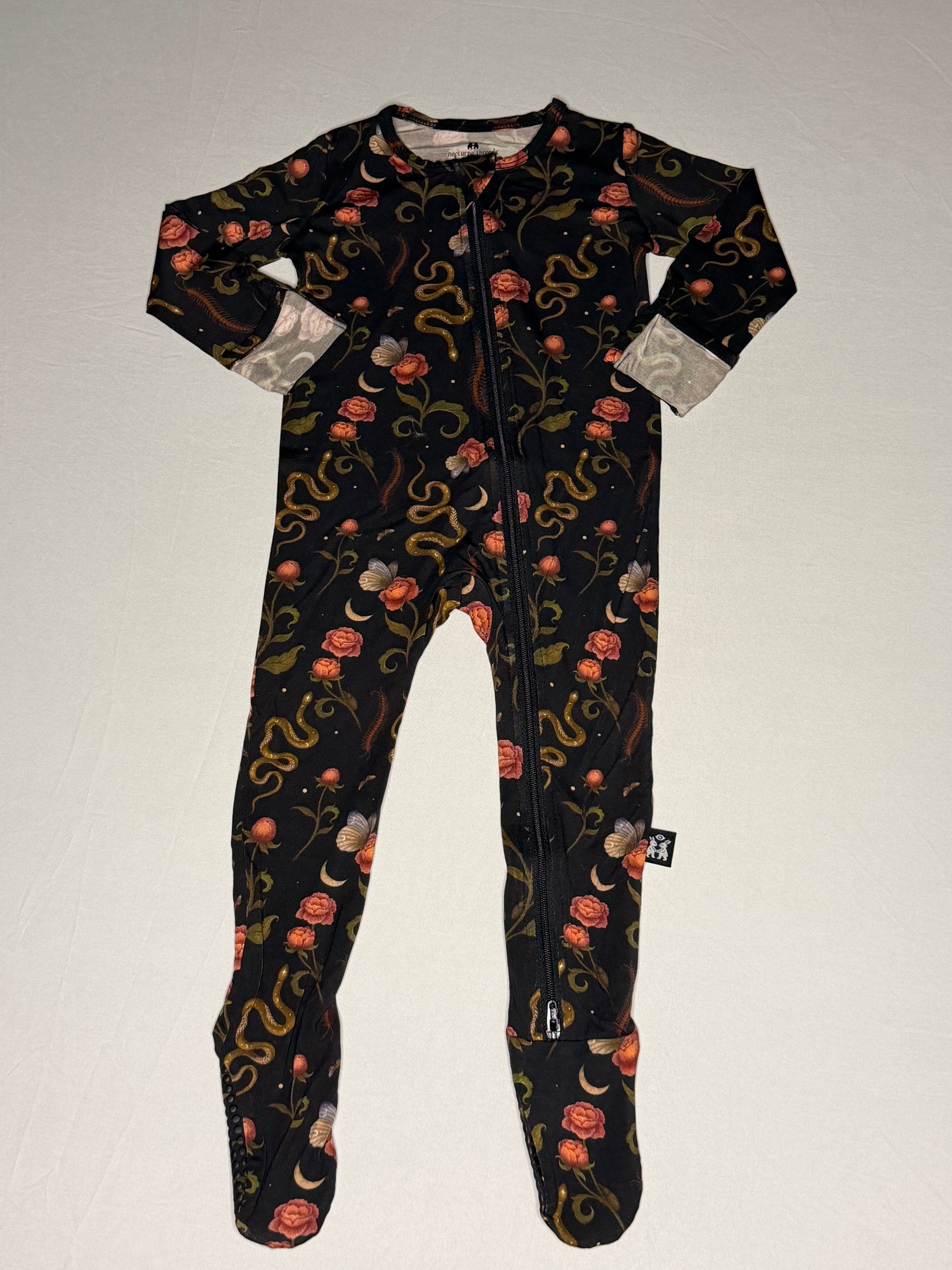 Black onesie with floral and snake pattern on a light gray background